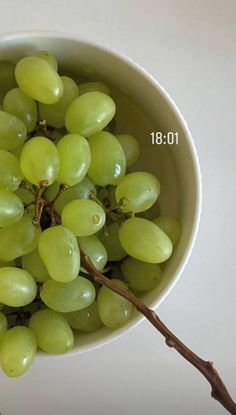 a white bowl filled with green grapes on top of a table