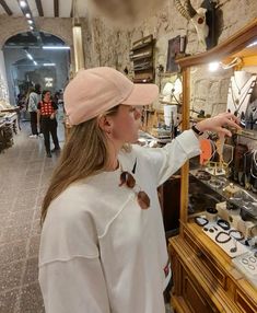 a woman in a pink hat is looking at items on a display case with other people standing around