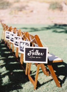 a row of wooden chairs sitting on top of a grass covered field next to each other