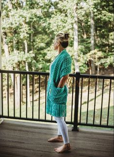 a woman standing on a porch looking up at the tree line in front of her