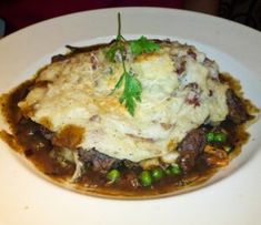 a white plate topped with mashed potatoes covered in gravy and garnished with parsley