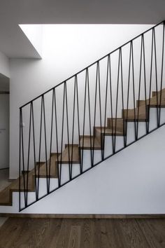 a stair case with wooden steps and metal handrails in an empty room next to a white wall