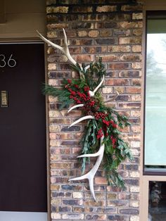 a deer antlers wreath hanging on the side of a brick building