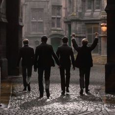 four men walking in the rain holding hands