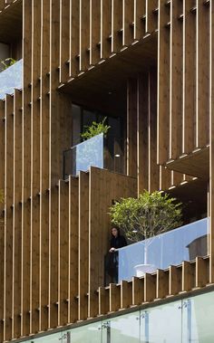 a man standing in the window of a tall building with wooden slats on it