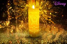 a yellow candle is lit in front of some gold sparkles and glittery lights