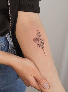 a woman's arm with a small flower tattoo on it