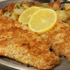 fish with potatoes and lemon wedges on a metal plate, ready to be eaten