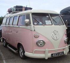 a pink and white vw bus parked in a parking lot