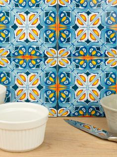 some bowls are sitting on a table with blue and yellow tiles in the back ground