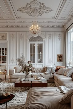 a living room filled with lots of furniture and a chandelier hanging from the ceiling