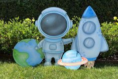 an inflatable toy is sitting on the grass next to two small planets and a rocket ship