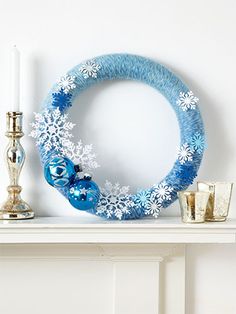 a blue wreath sitting on top of a mantle next to a candle and some glasses