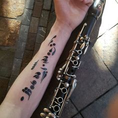 a person with a tattoo on their arm holding a flute