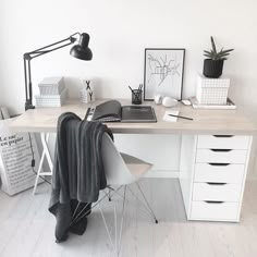 a white desk topped with a laptop computer next to a lamp and other office supplies