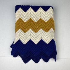 a crocheted blanket with blue, yellow and white stripes on it's edges