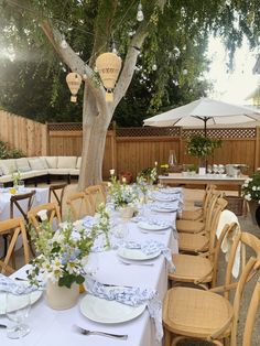 the table is set with white and blue place settings for an outdoor dinner or brunch party