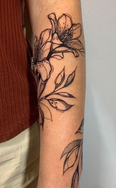 a woman's arm with flowers and leaves tattooed on the left side of her arm