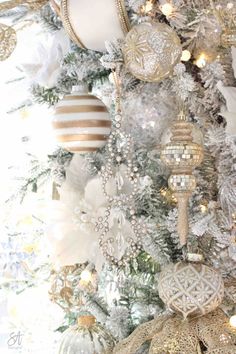 a white christmas tree with gold and silver ornaments