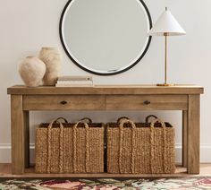 a wooden table with baskets under a round mirror