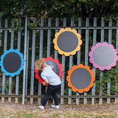 a young boy is playing with an umbrella in front of some colorful flowers on a fence