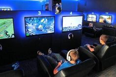 two young boys playing video games on the wii at an indoor gaming room with blue lighting