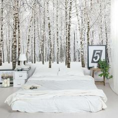 a white bed sitting in front of a wall covered in birch tree murals on it's side