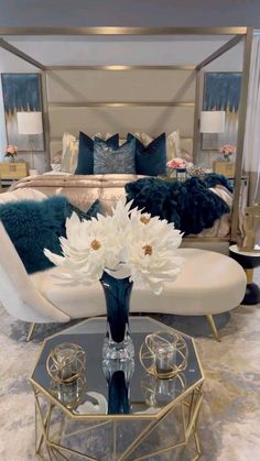 a white couch sitting next to a table with flowers on it in front of a bed