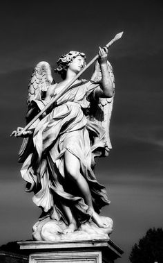 an angel statue holding a spear and shield