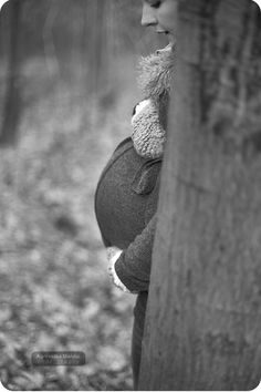 black and white photograph of a woman leaning against a tree in the woods with her eyes closed