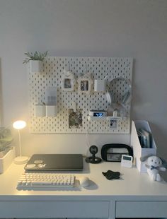 a white desk topped with a laptop computer next to a lamp and other office supplies