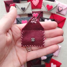 a hand holding a small piece of felt with hearts in the shape of envelopes