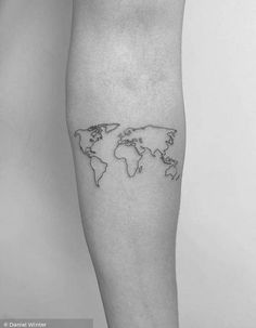 a black and white photo of a person's leg with a world map tattoo on it