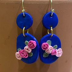 blue earrings with pink flowers on them hanging from hooks