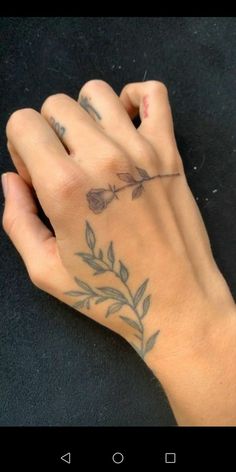 a person's hand with an arrow tattoo on their left wrist and the other hand is holding a cell phone