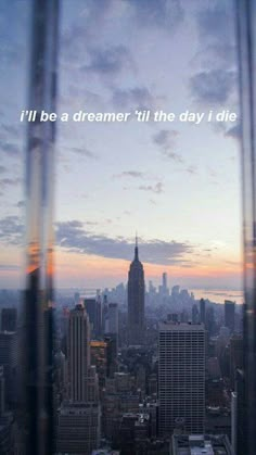 the city skyline is seen through a window with a quote on it that reads, i'll be a dream till the day i die