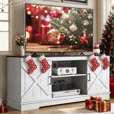 a flat screen tv sitting on top of a wooden entertainment center next to a christmas tree