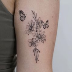 a woman's arm with flowers and butterflies tattoo on the back of her shoulder