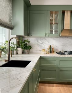 a kitchen with green cabinets and marble counter tops