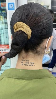 the back of a woman's head with tattoos on her neck and behind her ear