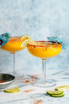 two glasses filled with orange margaritas and garnish