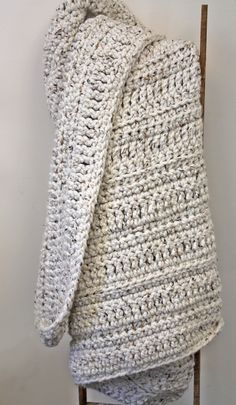 a white crocheted blanket sitting on top of a wooden chair with the text free mega tweed crochet throw pattern