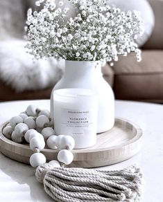 a white vase filled with baby's breath sitting on top of a wooden tray