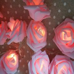 several pink roses are lit up on a polka dot tablecloth with candles in the middle