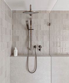 a shower head and hand held shower faucet in a bathroom with tiled walls