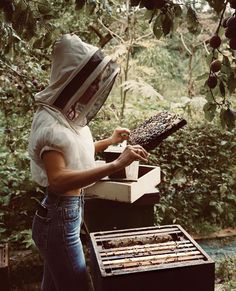 a woman wearing a bee suit and holding a hive box