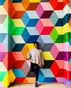 a woman standing in front of a colorful wall