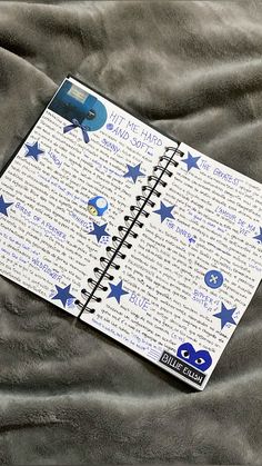 a spiral notebook with blue stars on it sitting on a gray sheet covered in text