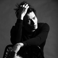 a black and white photo of a man sitting in a chair with his hands on his head