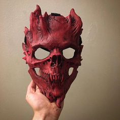 a hand holding up a red mask with spikes on it